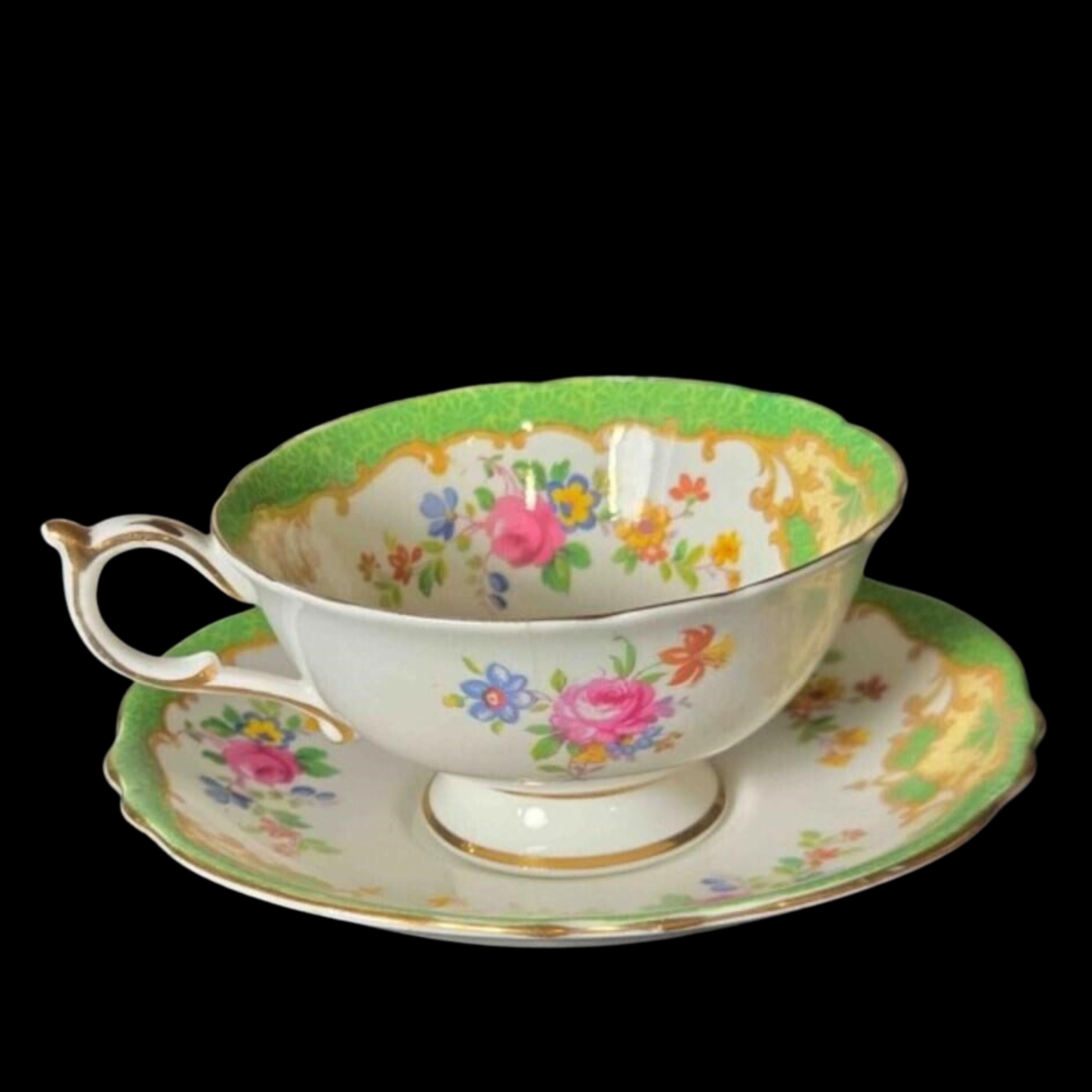 Decorative teacup and saucer with floral patterns on a black background
