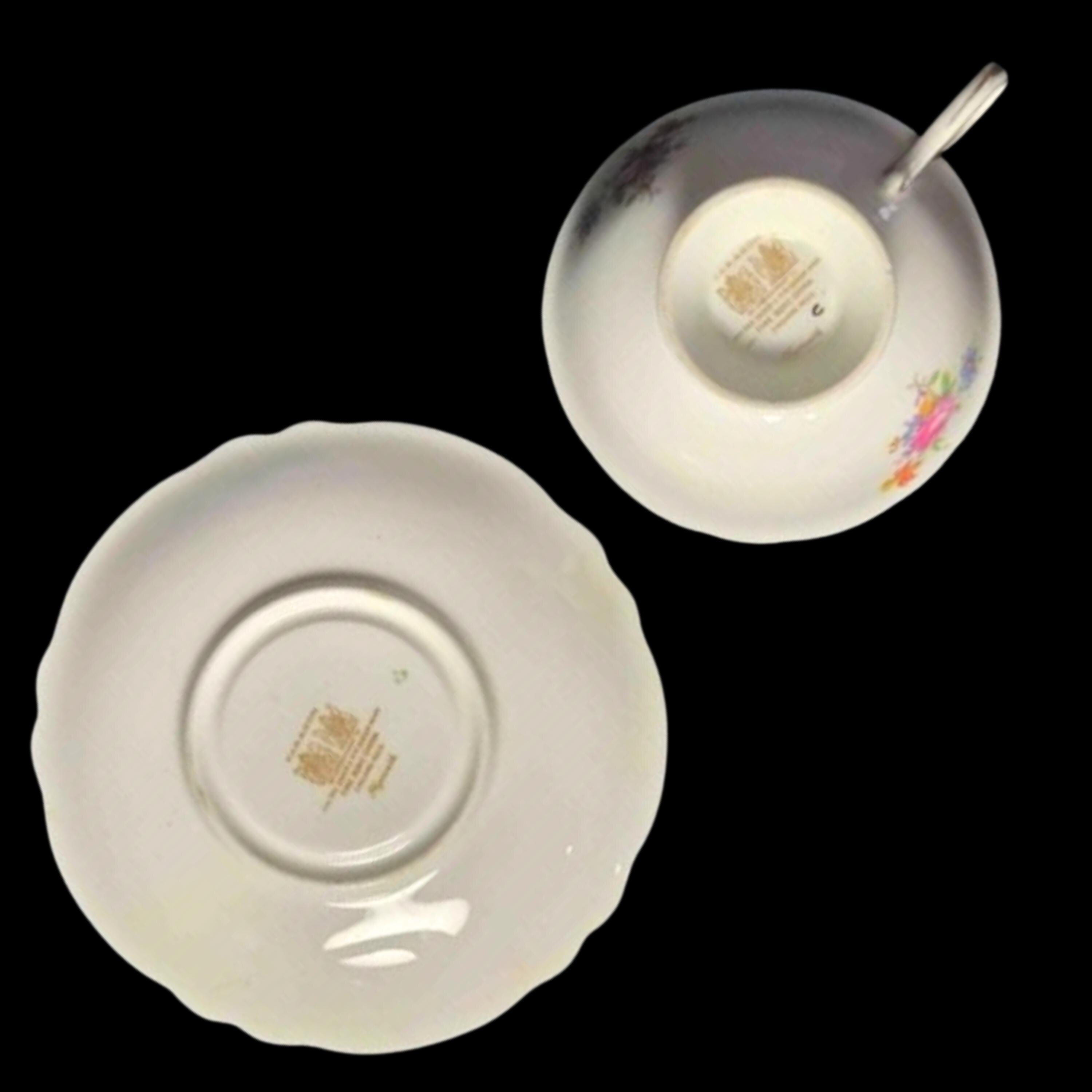 Bone china teacup and saucer showing maker's mark on back on a black background