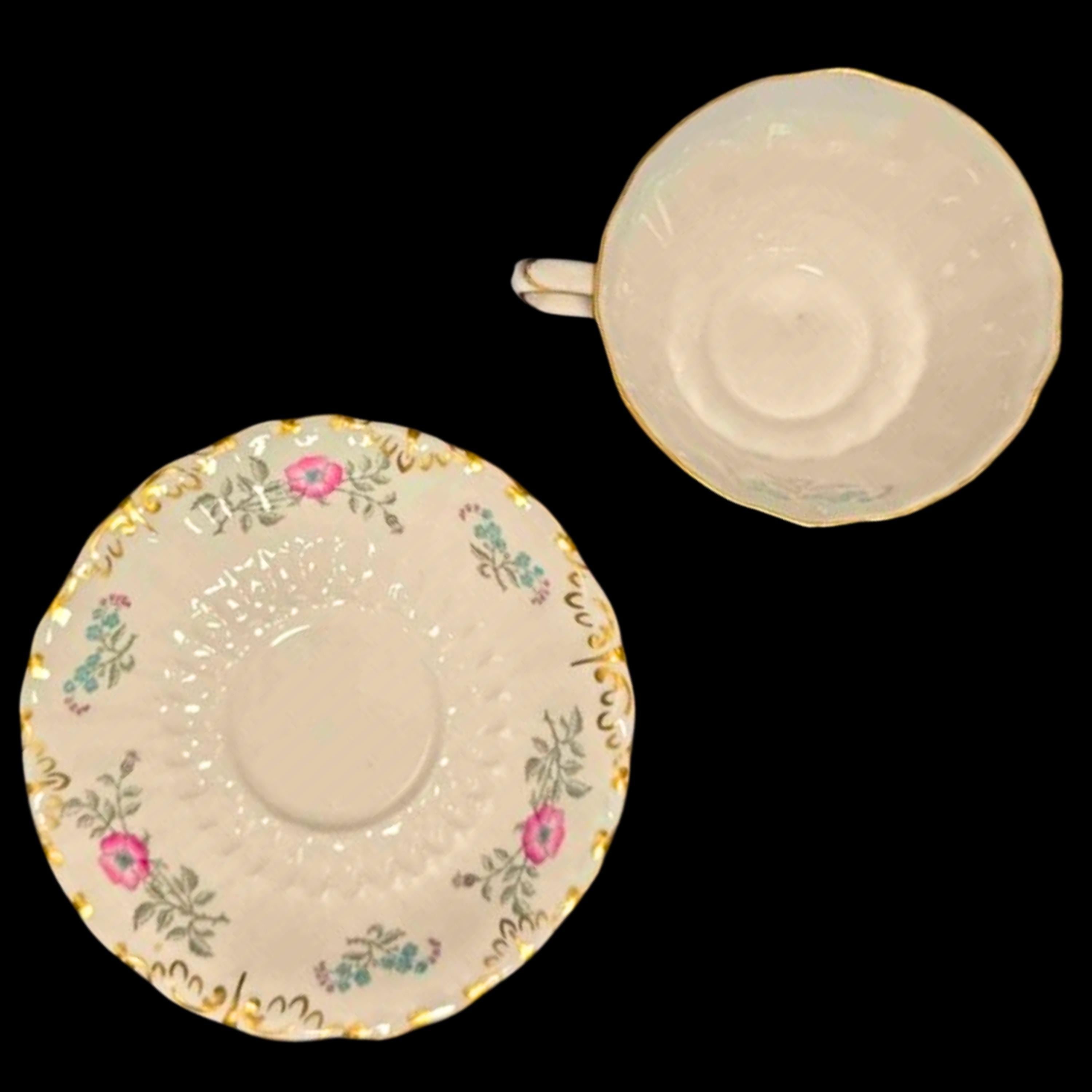 Ceramic teacup and saucer with floral patterns on a black background