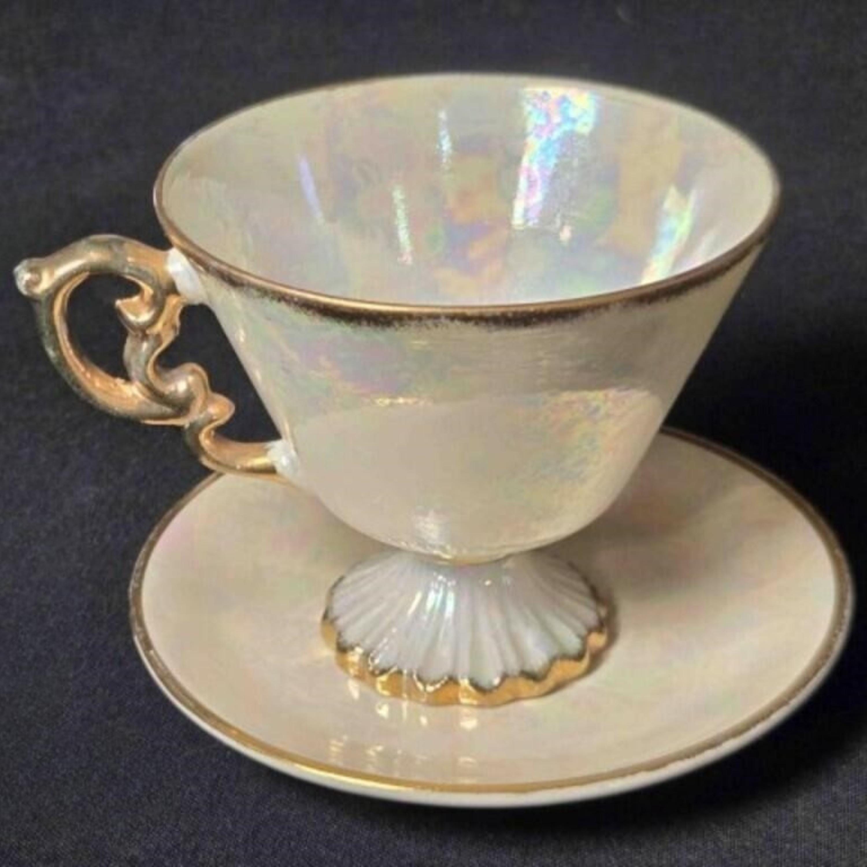 Opaline glass teacup and saucer with gold accents on a dark background