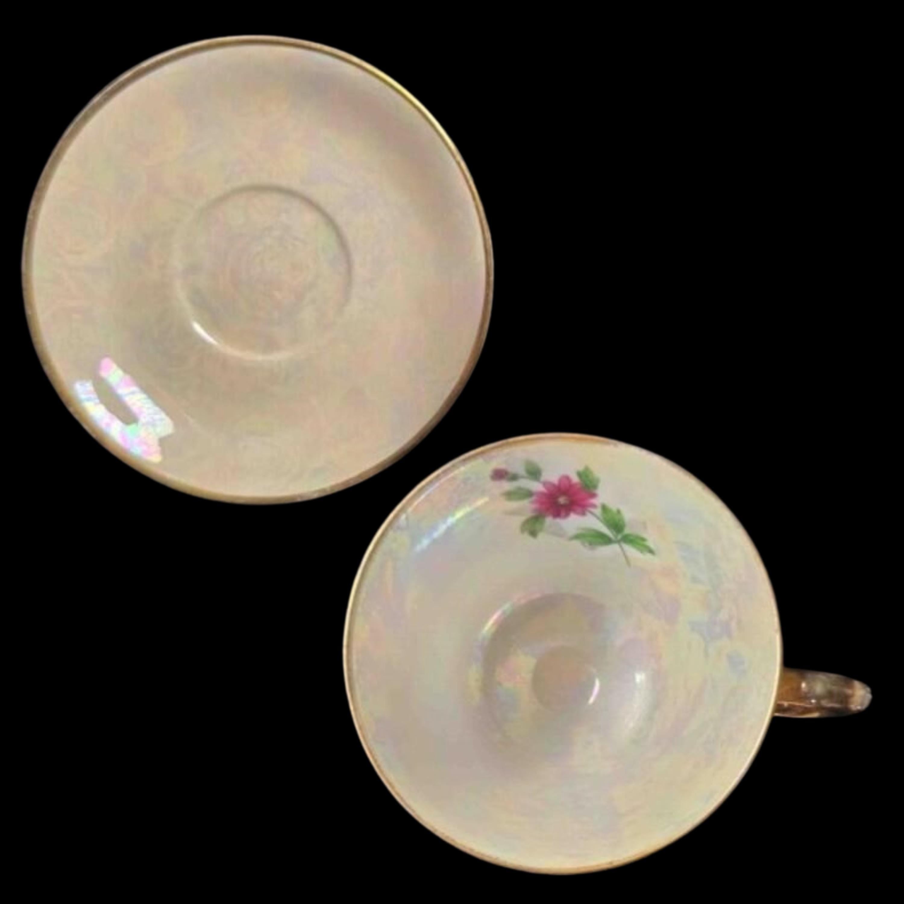 Iridescent teacup and saucer with floral design on a black background